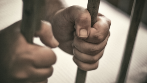 hands-clutching-jail-bars-